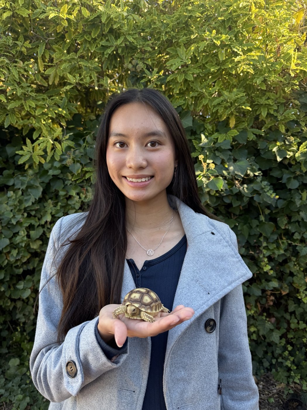 Pallas smiling outdoors while holding a small tortoise